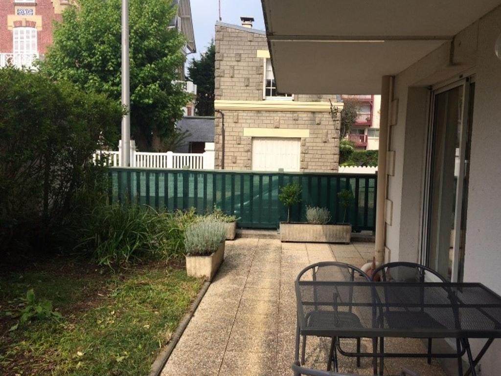 une terrasse couverte avec deux bancs et une clôture dans l'établissement Appartement 3 pièces, terrasse, aperçu mer, proche plage et centre de Villers-sur-Mer - FR-1-712-86, à Villers-sur-Mer