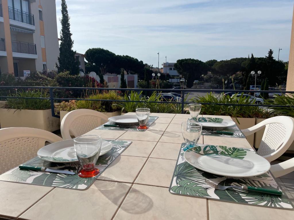 - une table avec des assiettes et des verres sur la terrasse dans l'établissement Appartement rénové, 4 couchages, grande terrasse, port de plaisance, à 200m de la plage - Argelès-sur-Mer - FR-1-309-473, à Argelès-sur-Mer