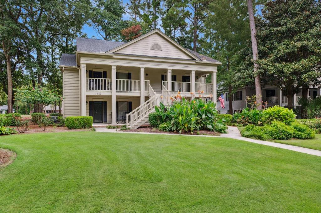 a house with a green lawn in front of it at 110-1 Fore Your Pleasure condo by Peace Vacations in Pawleys Island