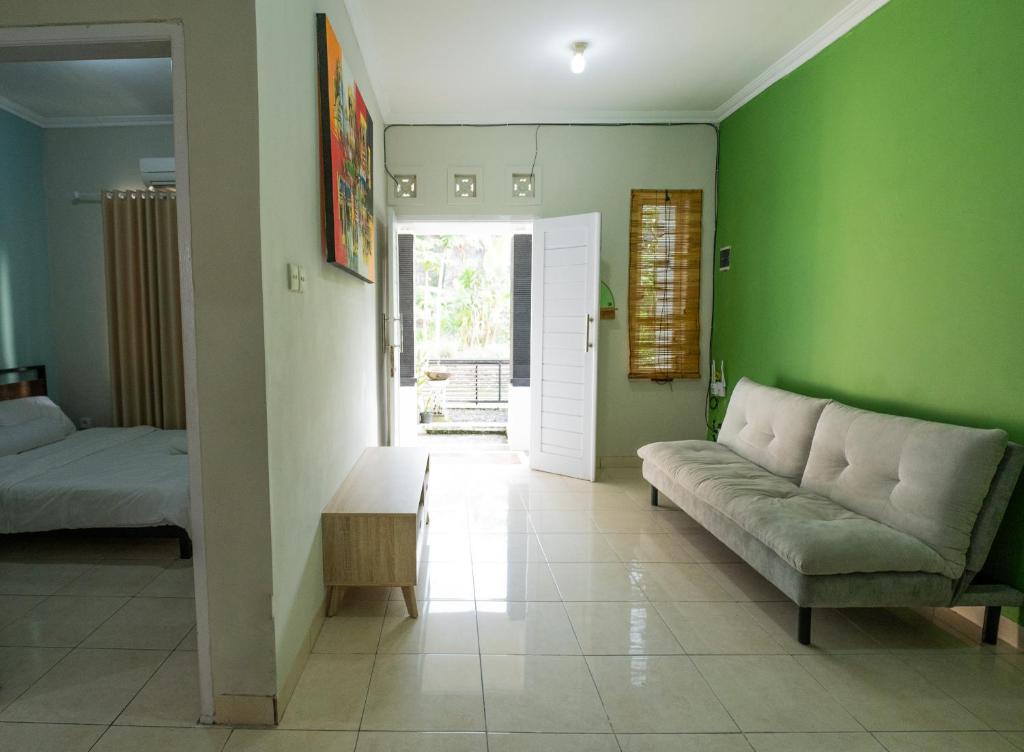 a living room with green walls and a couch at House Shizen I in Uluwatu
