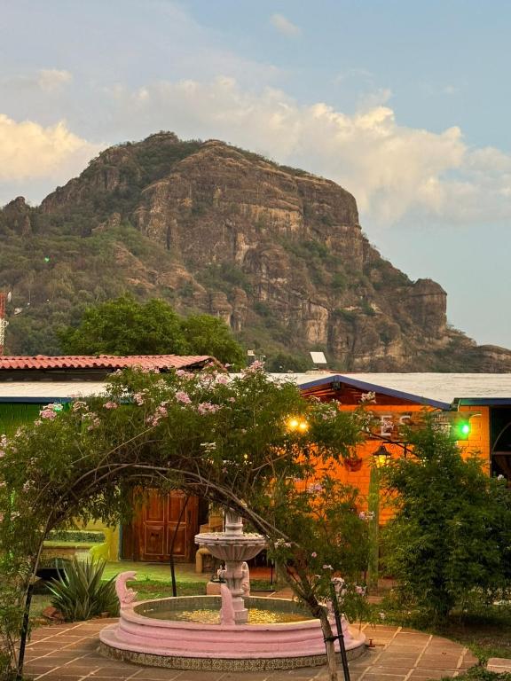 Im Hintergrund eines Gebäudes mit einem Brunnen erhebt sich ein Berg. in der Unterkunft Sampaz in Tepoztlán