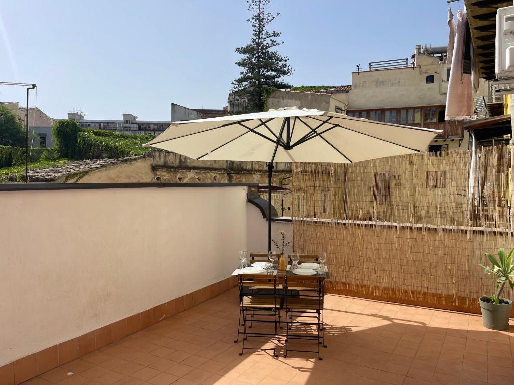 een tafel en stoelen onder een parasol op een balkon bij Casa Marì Holiday House in Palermo