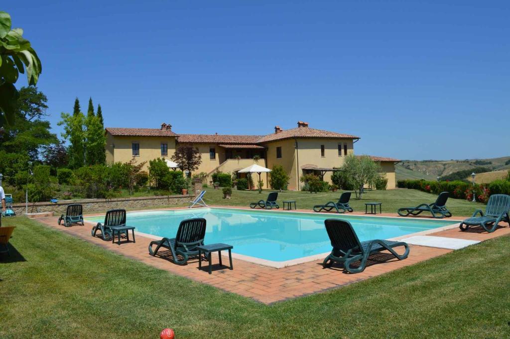 a swimming pool with chairs and a house at Apartment in Asciano - Toskana 50686 in Asciano