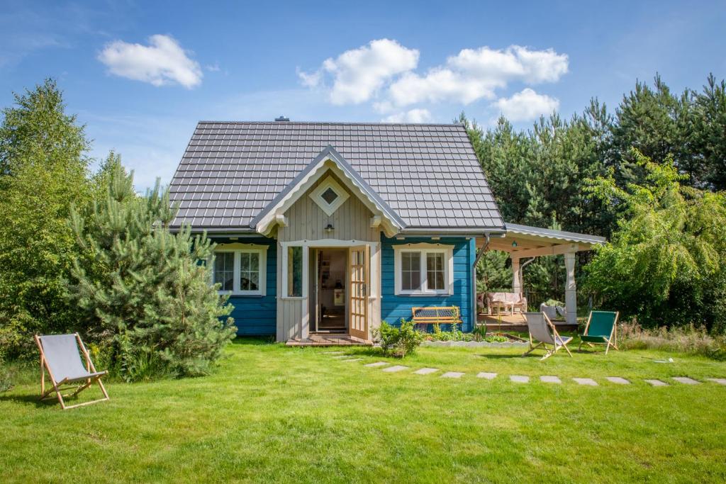 a blue house with chairs in the yard at Niebieski Domek nad Marychą in Stanowisko
