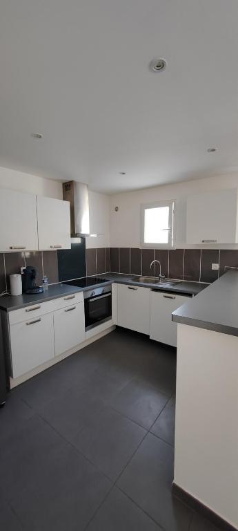 une grande cuisine avec des armoires et des appareils blancs dans l'établissement Maison de vacances, à Saint-Clément-de-Rivière