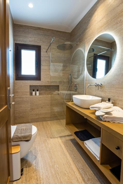 a bathroom with a sink and a toilet and a mirror at Elite Luxury Villas in Afiartis
