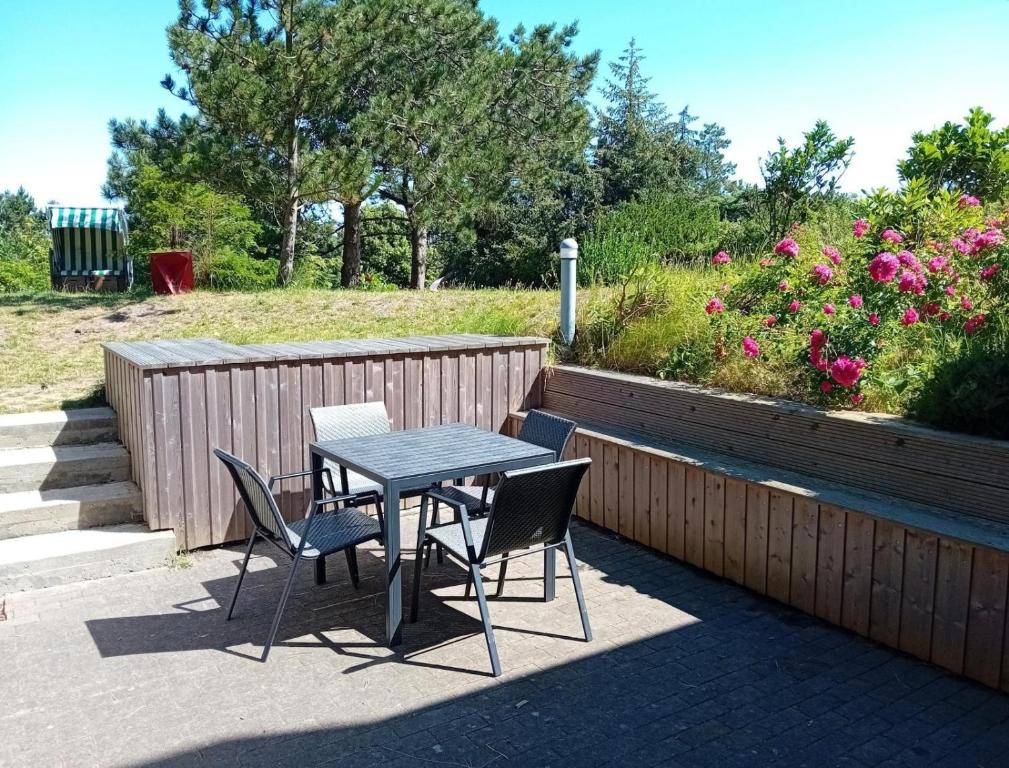 einen Tisch und Stühle auf einer Terrasse mit Blumen in der Unterkunft Unterdeck in Wittdün