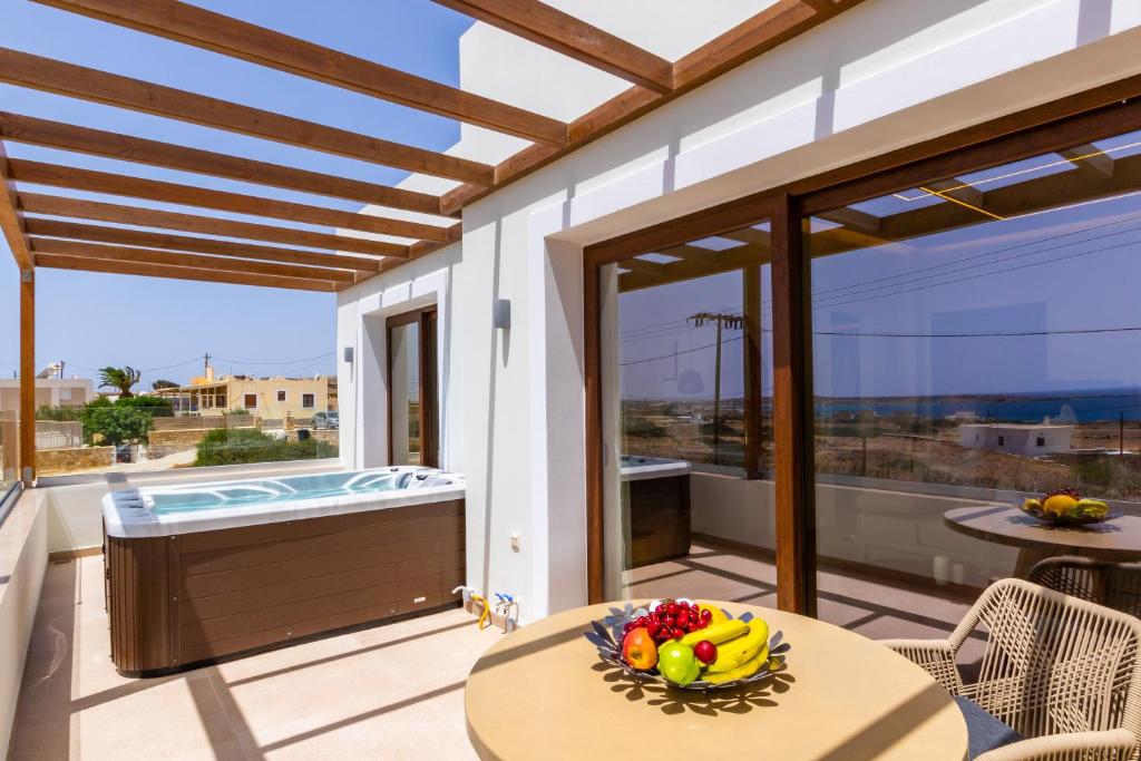 a patio with a tub and a table with a bowl of fruit at Elite Luxury Villas in Afiartis