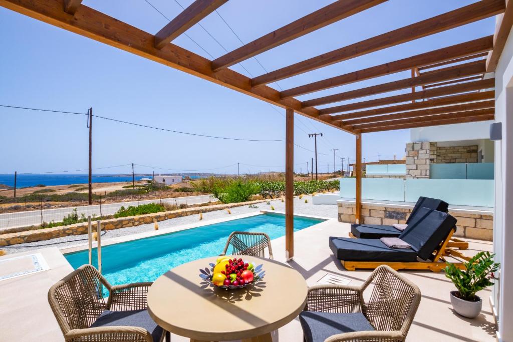 a patio with a table and chairs and a pool at Elite Luxury Villas in Afiartis