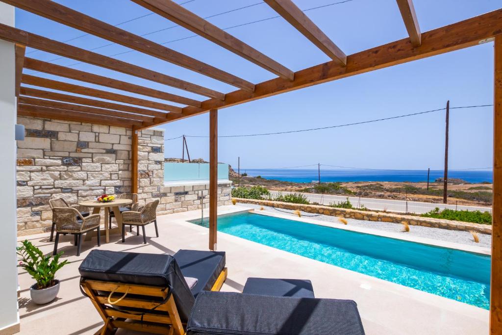 a villa with a swimming pool and a patio with a table and chairs at Elite Luxury Villas in Afiartis