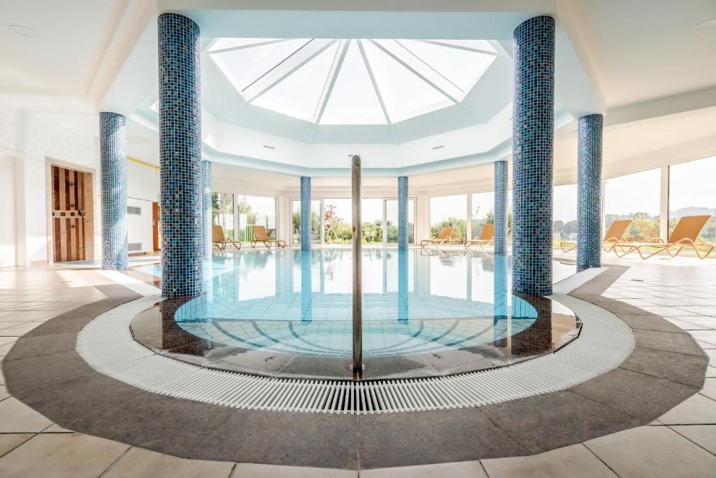 duży basen z niebieskimi kolumnami w budynku w obiekcie Hotel Römerstein w mieście Loipersdorf bei Fürstenfeld