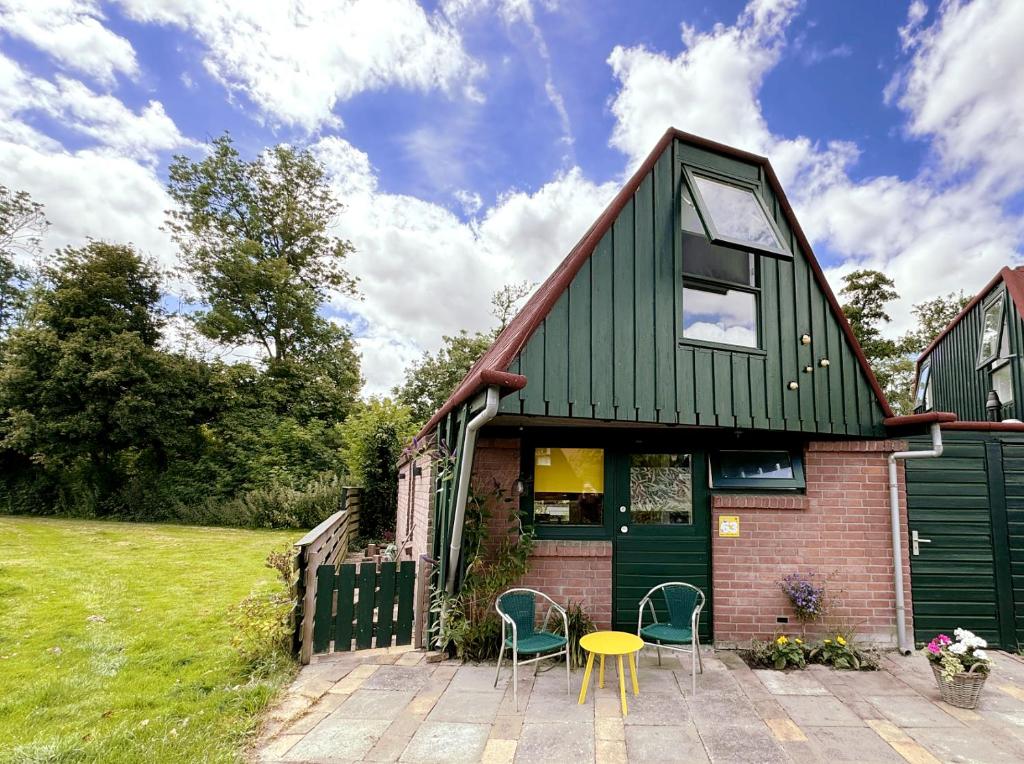 una casa con tetto verde e tavolo e sedie di Happy Little Maya Bee a Nieuwe-Niedorp