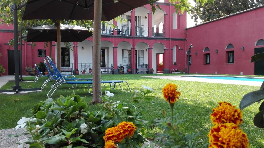 un edificio rosa con sombrilla y flores en el patio en Aparthotel Can Gallart, en Santa Coloma de Farners