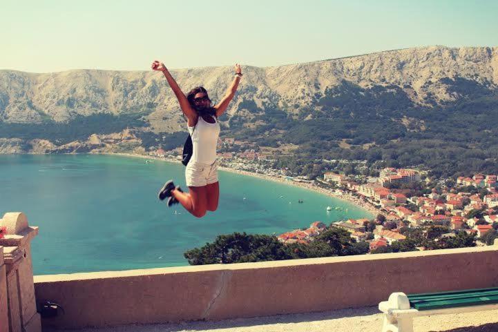 a woman jumping in the air on a ledge at Apartments Dupin in Baška