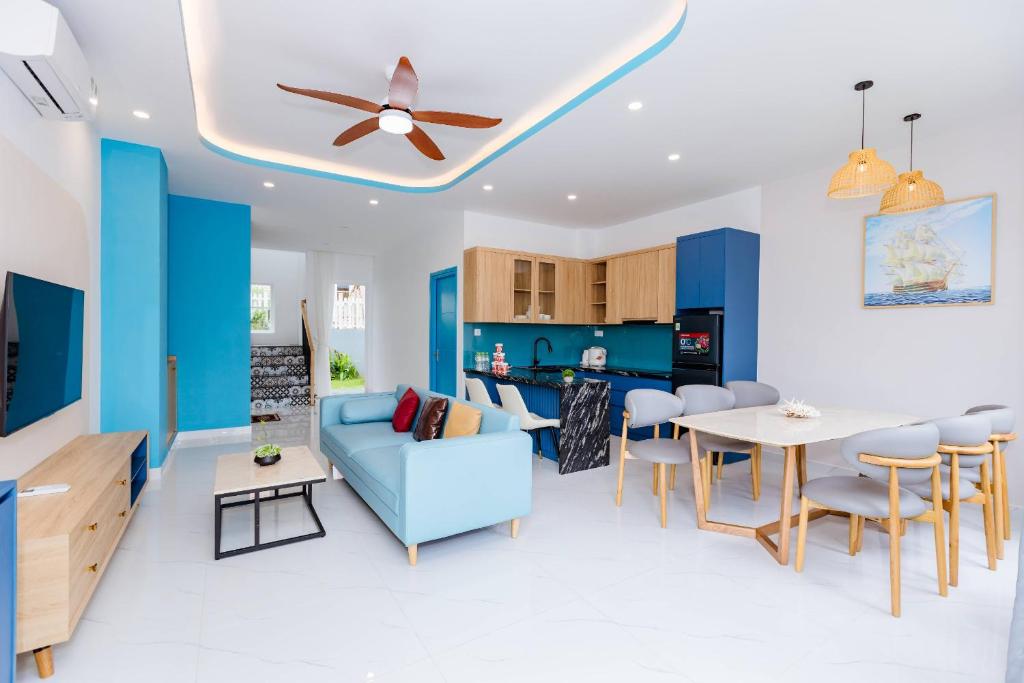 Una sala de estar con un sofá azul y una mesa. en LuxVilla 4BR NovaWorld Phan Thiết, en Bình Tú