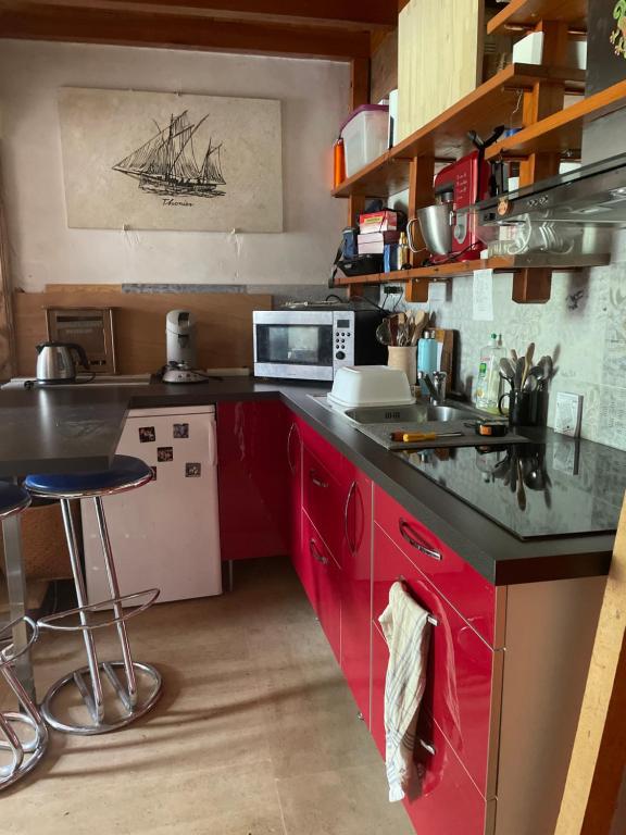 une cuisine avec des armoires rouges et un comptoir noir dans l'établissement Studio meublé campagne, à Saint-Pey-de-Castets