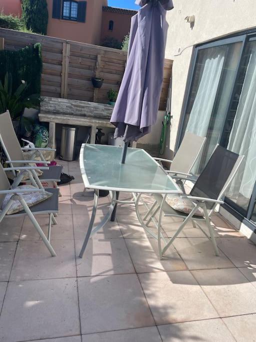 une table en verre et deux chaises sur la terrasse dans l'établissement Apt Rez de jardin piscine dans résidence, à Fréjus