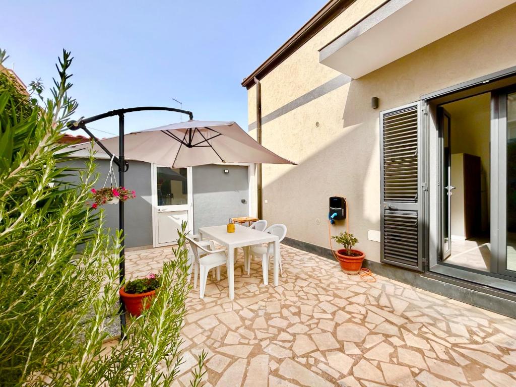 a patio with a white table and an umbrella at La Casetta di Eli in Siracusa
