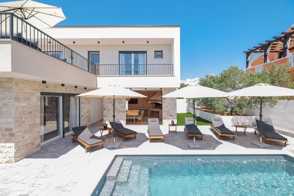 a villa with a swimming pool and umbrellas at CROWONDER Villa Bura with Heated Swimming Pool and Jacuzzi in Privlaka