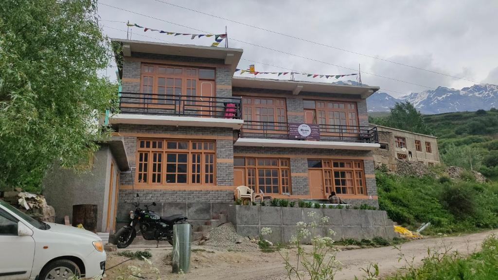 SissuBros Hostel & Cafe, Sissu的一栋房子前停着一辆摩托车