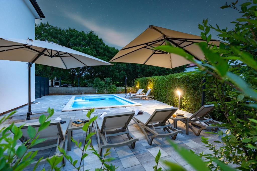 a patio with two umbrellas and a swimming pool at Apartment Mara by EL-PI TOURS in Malinska
