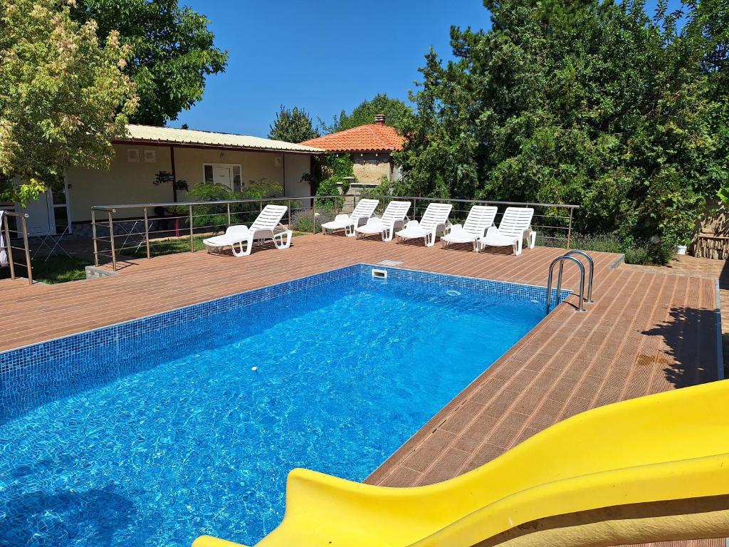 a swimming pool with lounge chairs next to a house at Guest House Nevena in Shabla