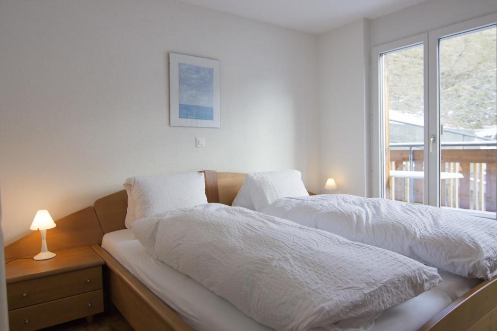 um quarto com 2 camas com lençóis brancos e uma janela em Fee-rien em Saas-Fee