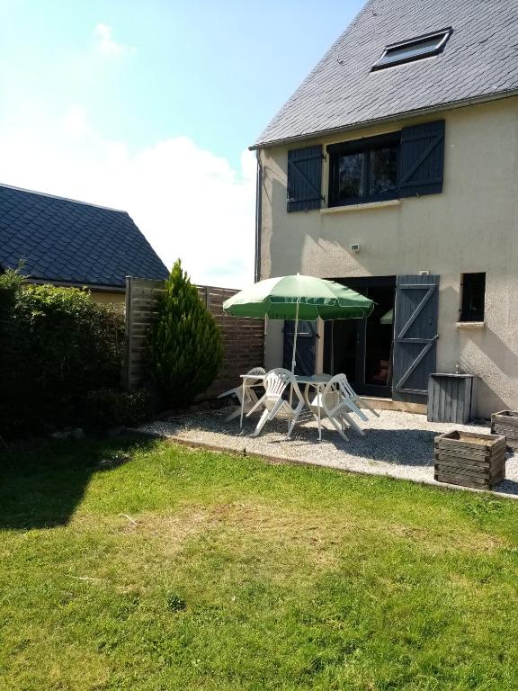 - une terrasse avec un parasol vert et 2 chaises dans l'établissement Les Caribous, à Chastreix