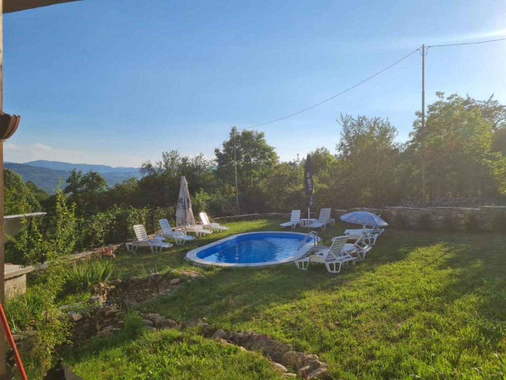 a yard with a swimming pool and chairs and a fire pit at Къщи за гости под орехите in Tryavna