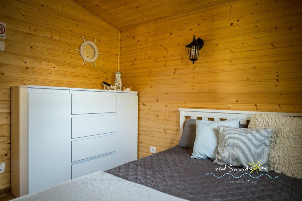 a bedroom with a bed and a wooden wall at Domki Letniskowe NAD ŚNIARDWAMI BARBARA MAJKRZAK in Nowe Guty