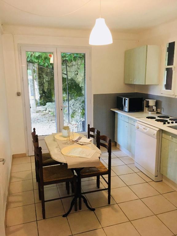 une cuisine avec une table et des chaises ainsi qu'une cuisine avec une table et une table dans l'établissement Au fil du Chassezac #Kiwi, à Chambonas