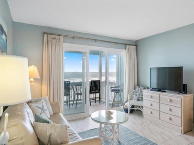 a living room with a couch and a television and a table at Beach Bliss condo in Carolina Beach