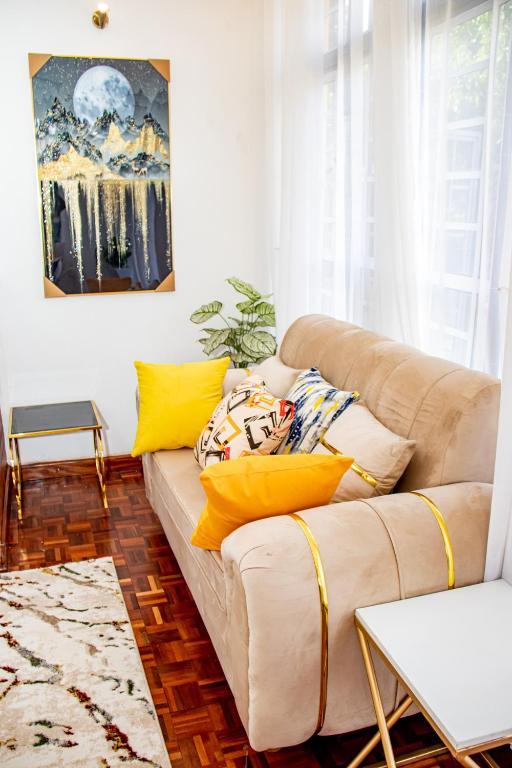 a living room with a couch with yellow pillows at Kathy's Serene Suites in Nairobi