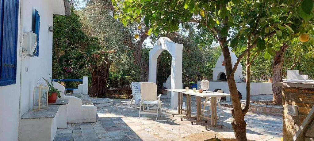 a patio with a table and chairs and a tree at Beach House Paou in Argalasti