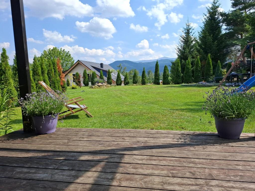 a deck with two potted plants and a playground at Dom uKromki z kominkiem i widokiem na Śnieżkę in Sosnówka