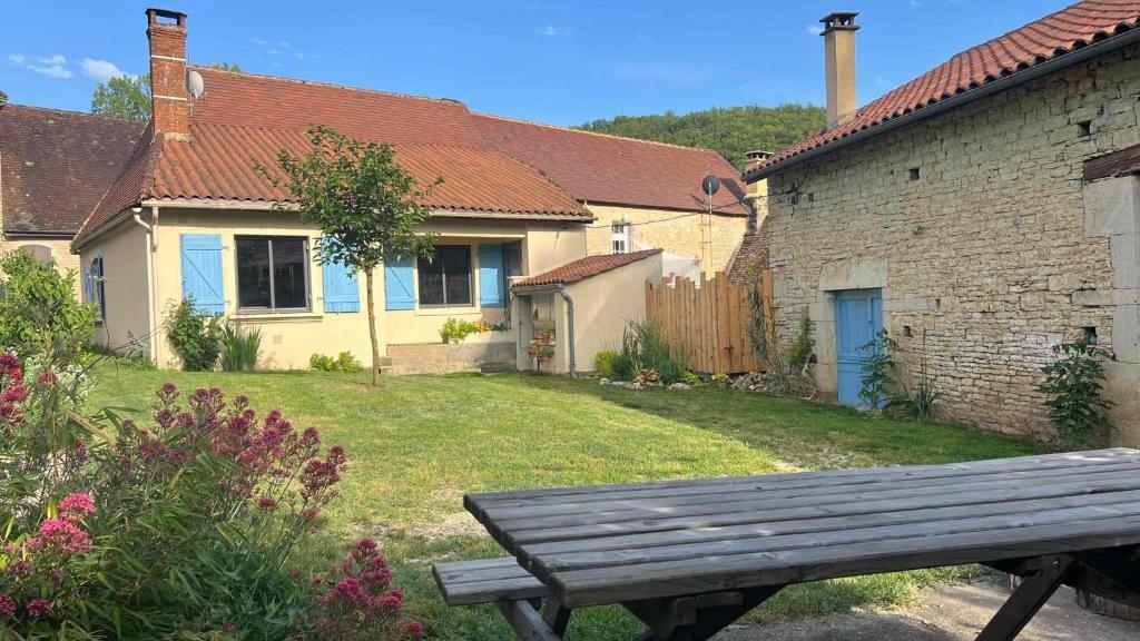 a wooden bench sitting in front of a house at Maison de village avec jardin clos in Bouzic