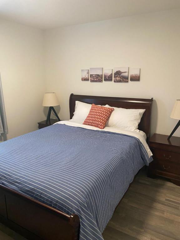 a bed with a blue and white striped blanket and two lamps at The Hideaway Cottage with Private trails in Waweig