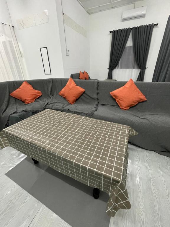 a couch with orange pillows on it in a living room at Homestay Alyaa Bera Triang in Teriang