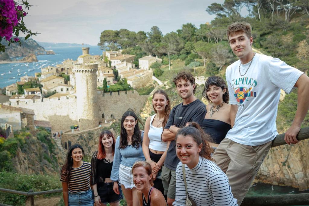 un grupo de personas de pie en frente de un castillo en Mana Mana Youth Hostel, en Tossa de Mar