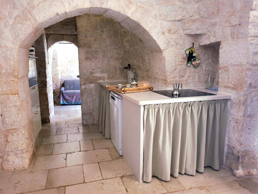 a kitchen with a sink and a stone wall at Trullo Bosco Libero Ostuni in Ostuni