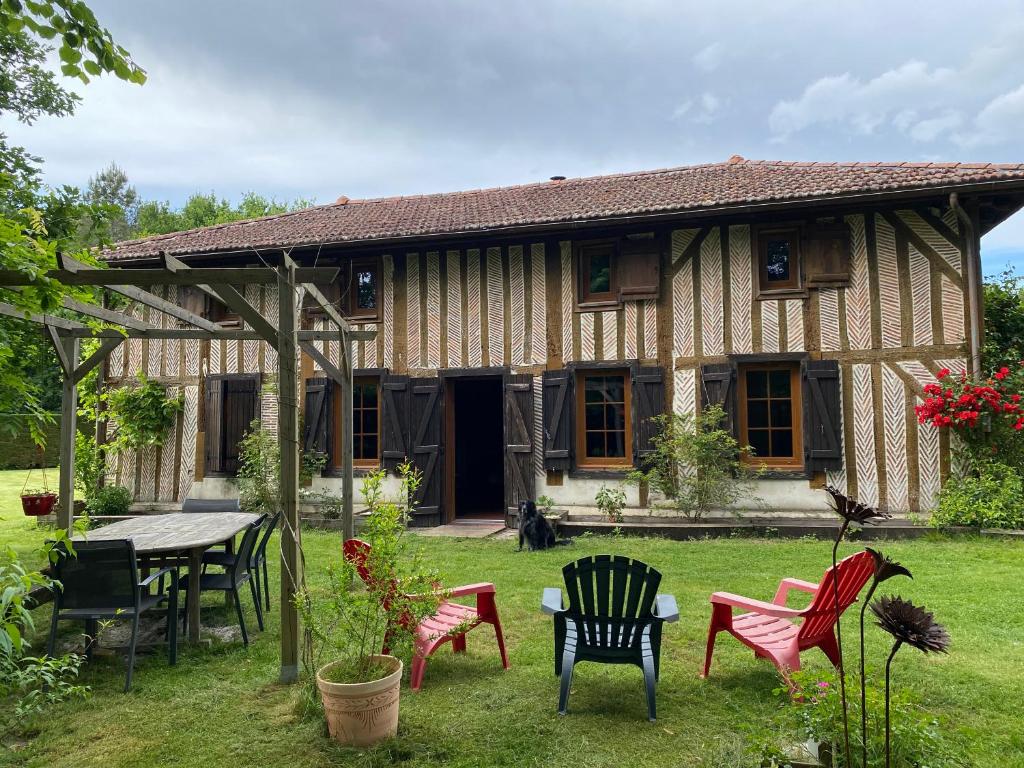 une maison avec des chaises et une table dans la cour dans l'établissement Le chêne magique 40200 Léontine, à Pontenx-les-Forges
