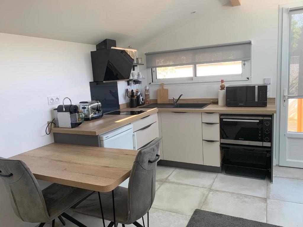 une cuisine avec une table en bois et un micro-ondes dans l'établissement Studio cosy proche plages, à Anglet