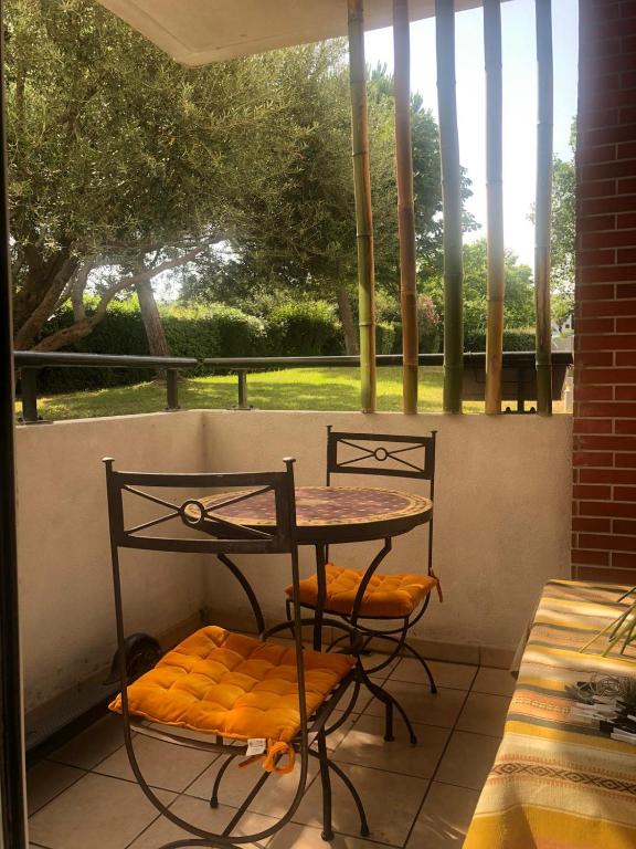 - une table et deux chaises sur une terrasse couverte avec une fenêtre dans l'établissement studio avec parking Montpellier, à Montpellier