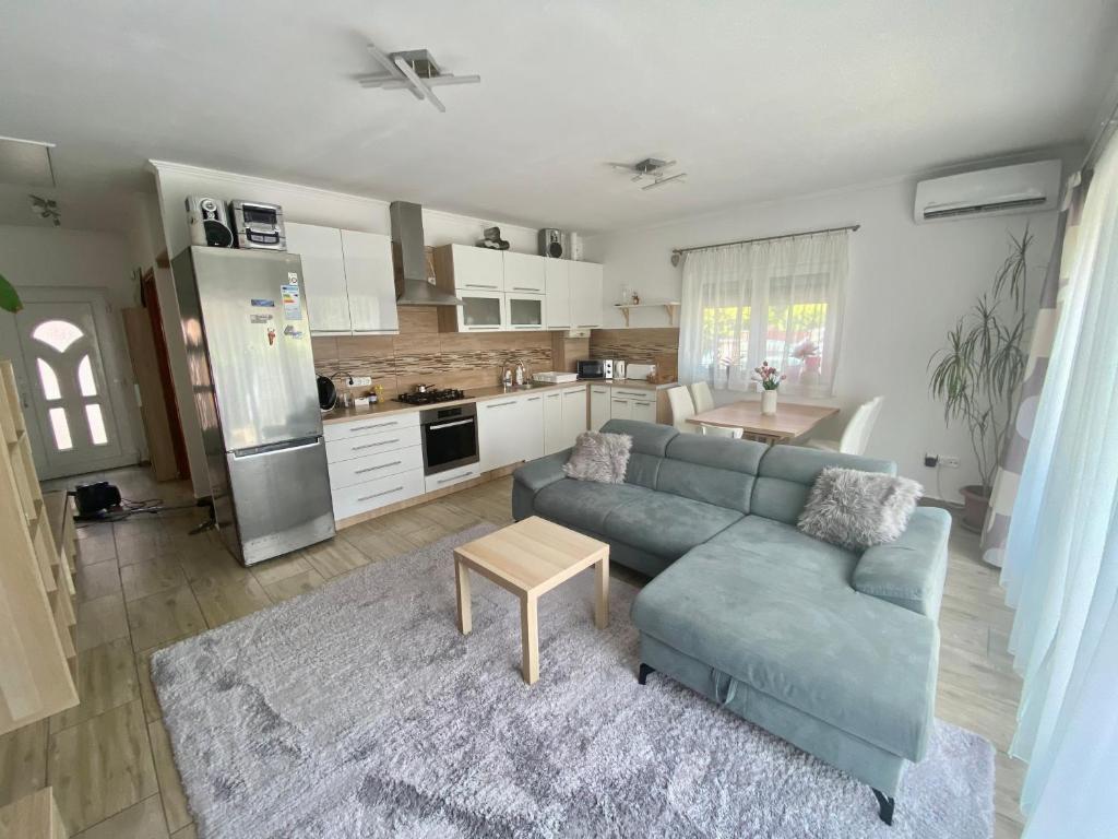 a living room with a blue couch and a kitchen at Deák Apartman Gárdony in Gárdony