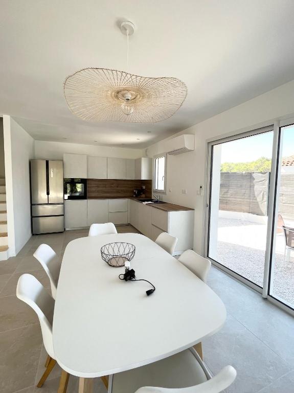 une salle à manger blanche avec une table et des chaises blanches dans l'établissement Villa avec piscine, vue dégagée sur la forêt, à Fuveau