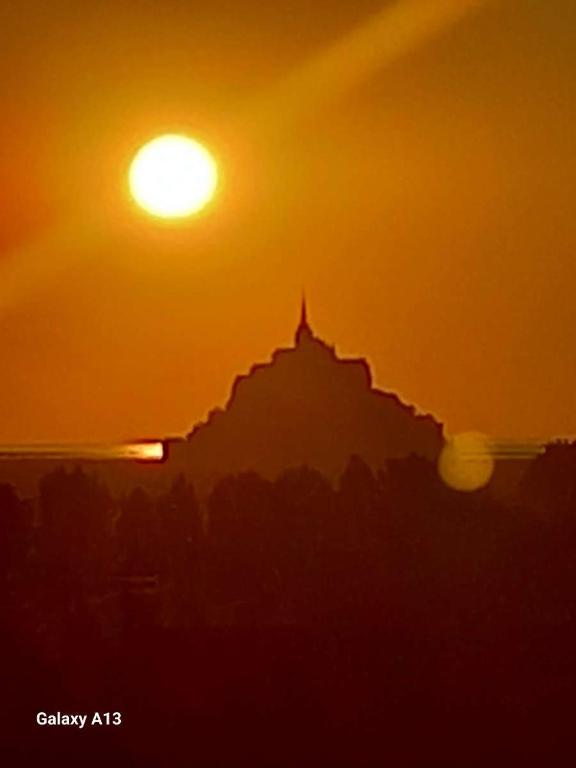 une silhouette d'un bâtiment avec le coucher du soleil en arrière-plan dans l'établissement Maison 8 personnes vue sur le Mont Saint Michel, à Huisnes-sur-Mer