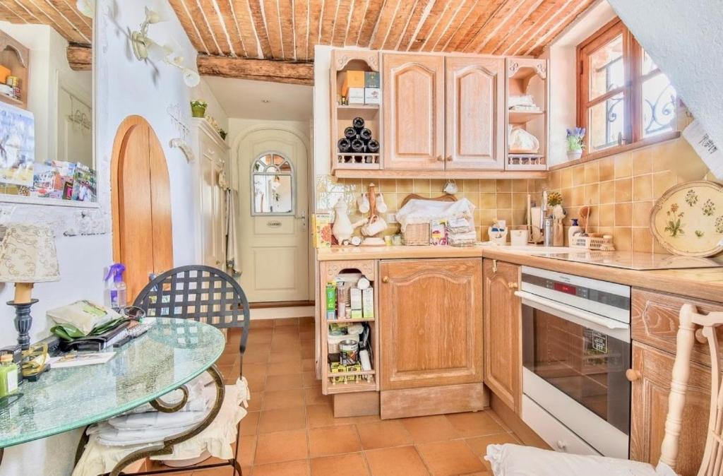 une cuisine avec des placards en bois et une table en verre dans l'établissement F2 Vieux Village Roquebrune Cap Martin RCM, à Roquebrune-Cap-Martin