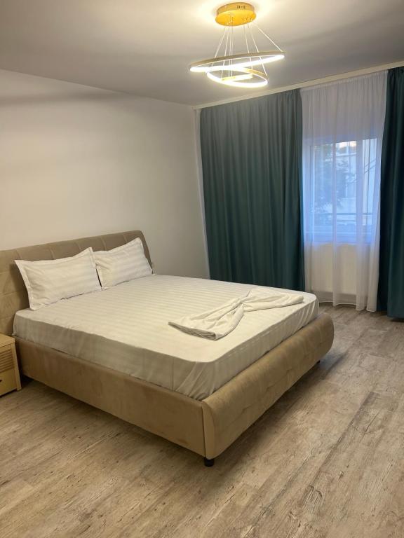 a bedroom with a large bed with green curtains at Apartament Emma in Mangalia