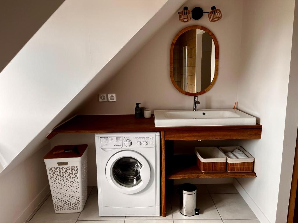 a bathroom with a sink and a washing machine at Maison paisible et charmante in Vendoeuvres