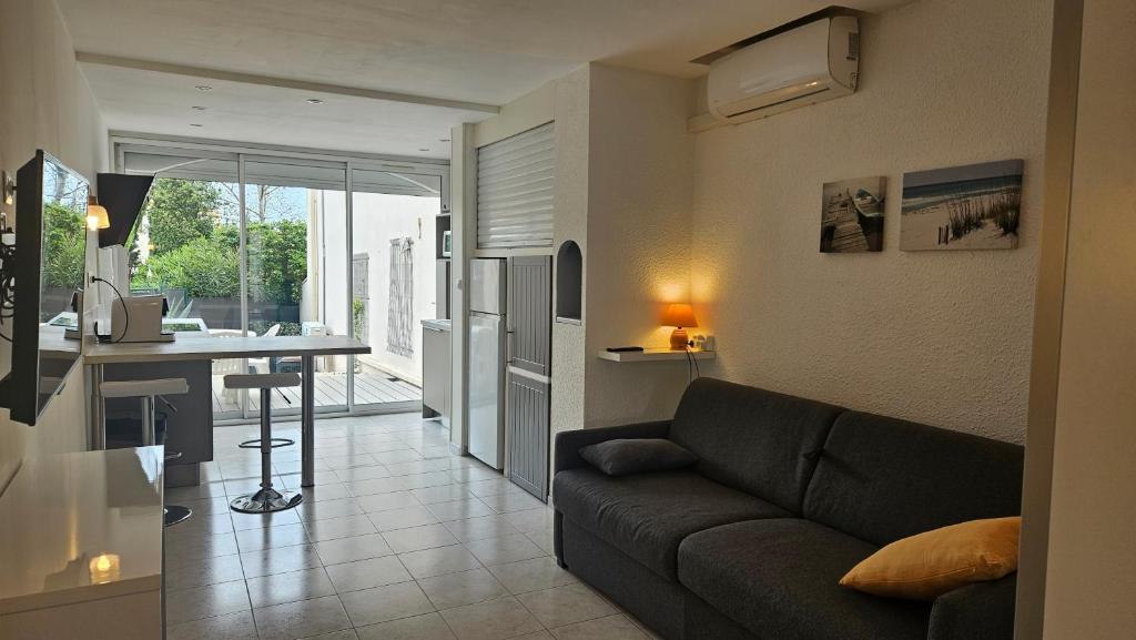 a living room and kitchen with a couch and a table at Grand studio rénové avec terrasse et clim ! in Cap d'Agde